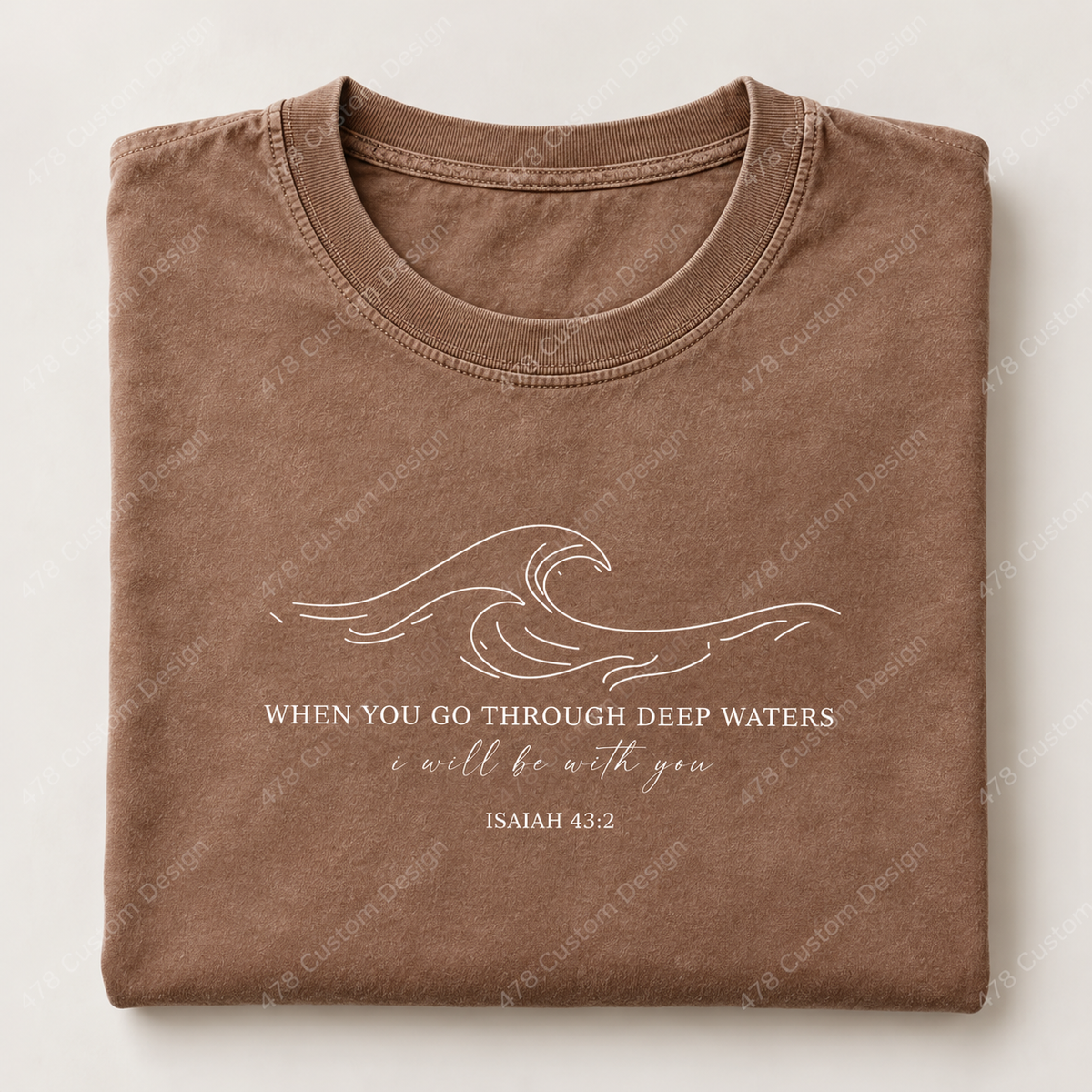 Folded brown shirt with white ocean wave and When You Go Through Deep Waters Isaiah 43:2 front design