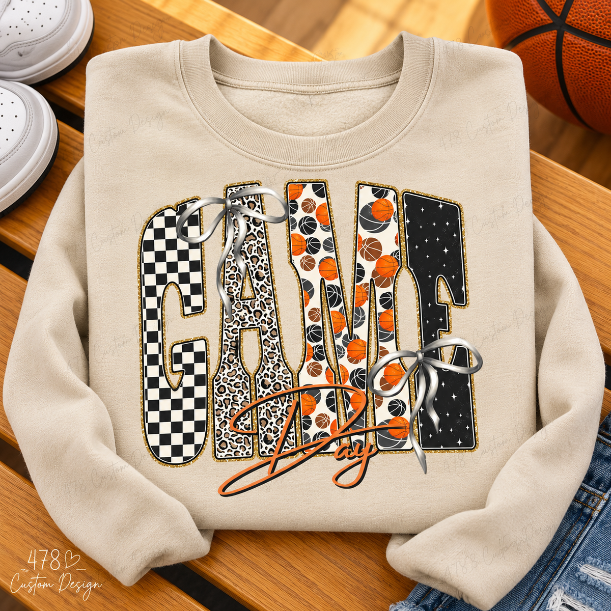 Sand sweatshirt with Basketball Game Day patterned letters and printed silver bows on a basketball-themed flatlay