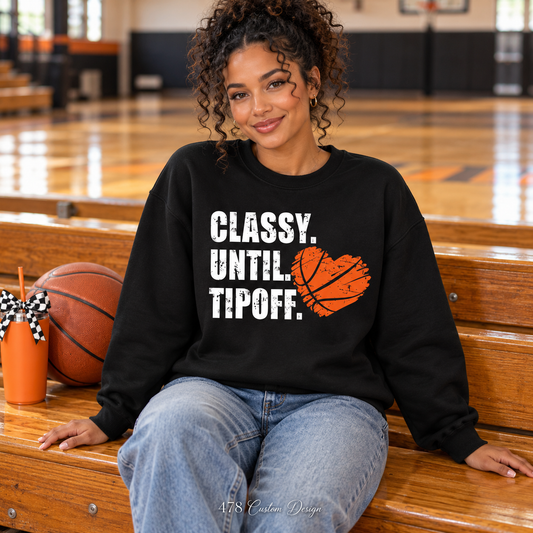 Woman seated courtside wearing black Classy Until Tipoff basketball heart sweatshirt