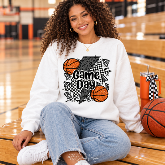 Seated woman wearing white Basketball Game Day sweatshirt courtside