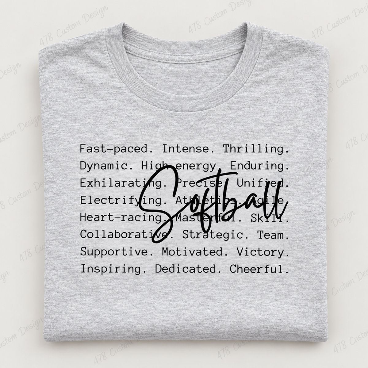 Softball script over motivational words on gray folded shirt